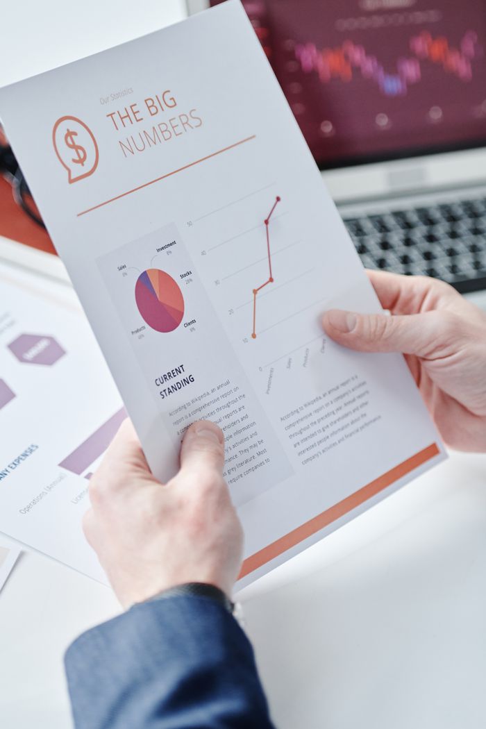 why-choose-us Close-up of hands holding a business report with data charts and graphs displaying financial information.