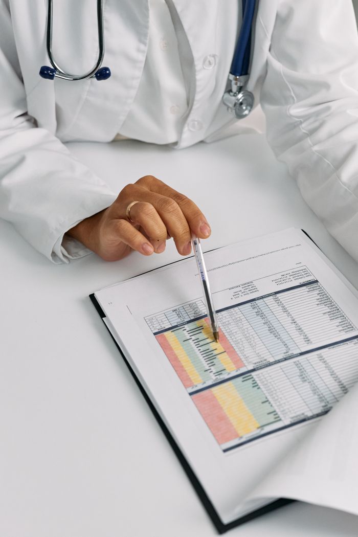 gallery-3 Doctor analyzing patient charts with a pen, focusing on data points for medical insights.